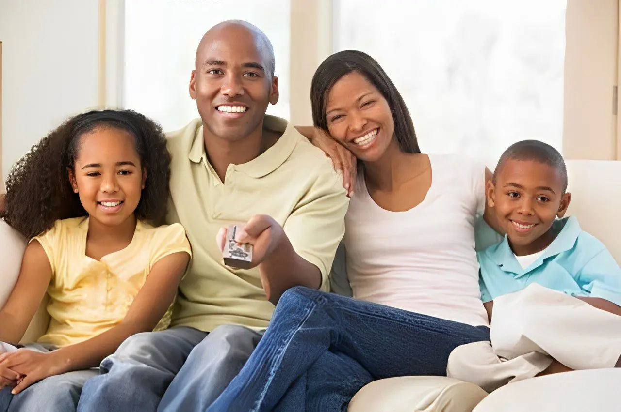 A family sitting on the couch watching tv