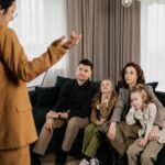 a man is talking to a family sitting in a sofa