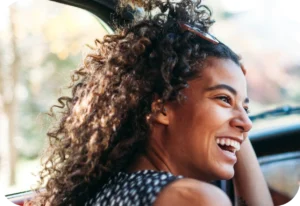 Happy woman with curly hair in car.