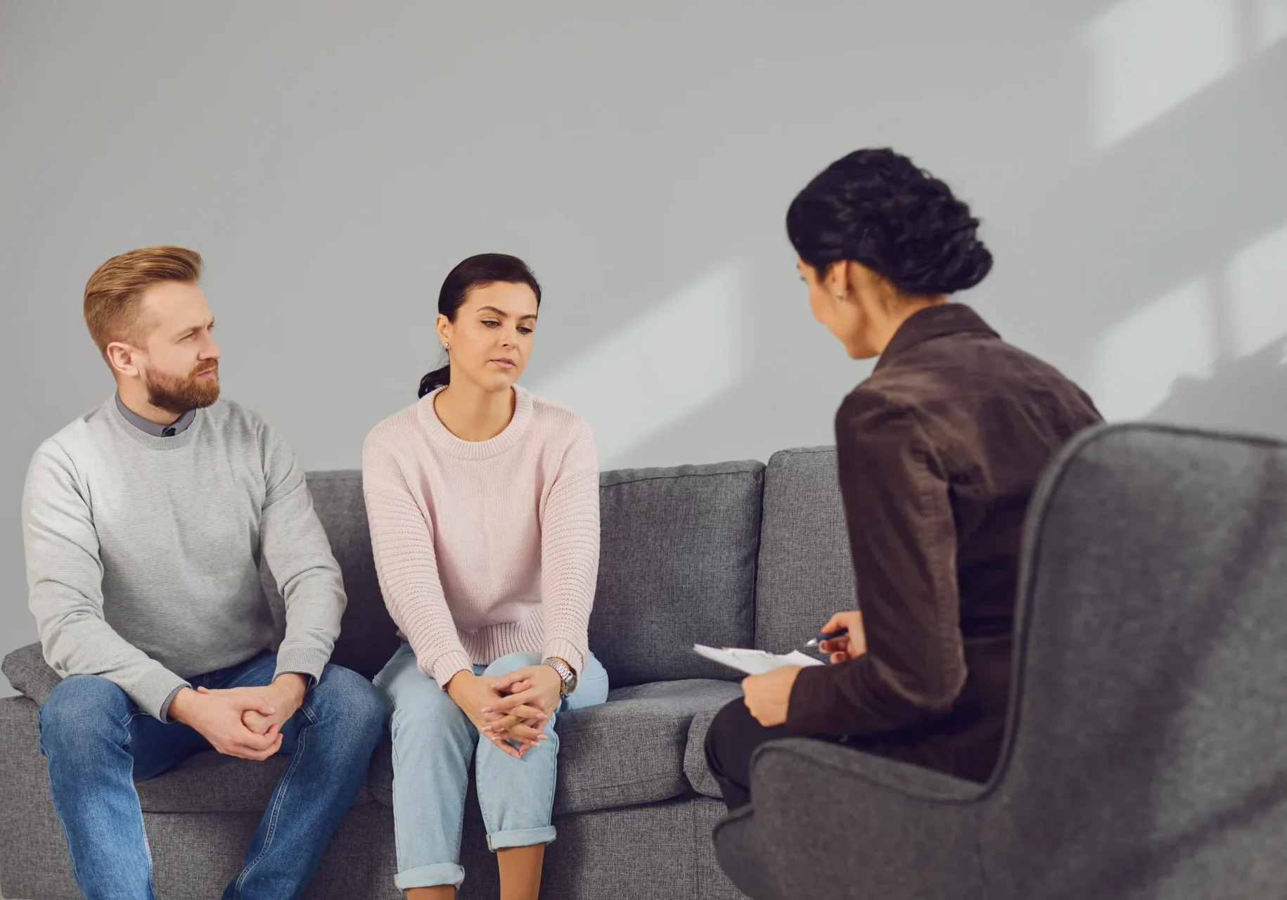 A woman sitting on the couch with two people.