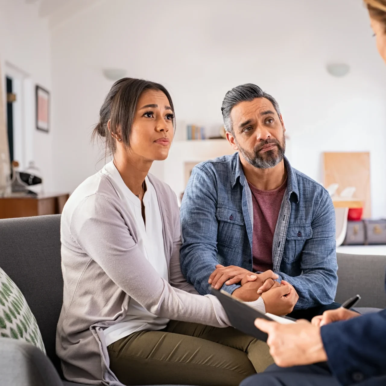 A man and woman sitting on the couch talking to another man.