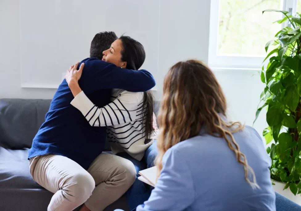 Two people hugging while others watch.